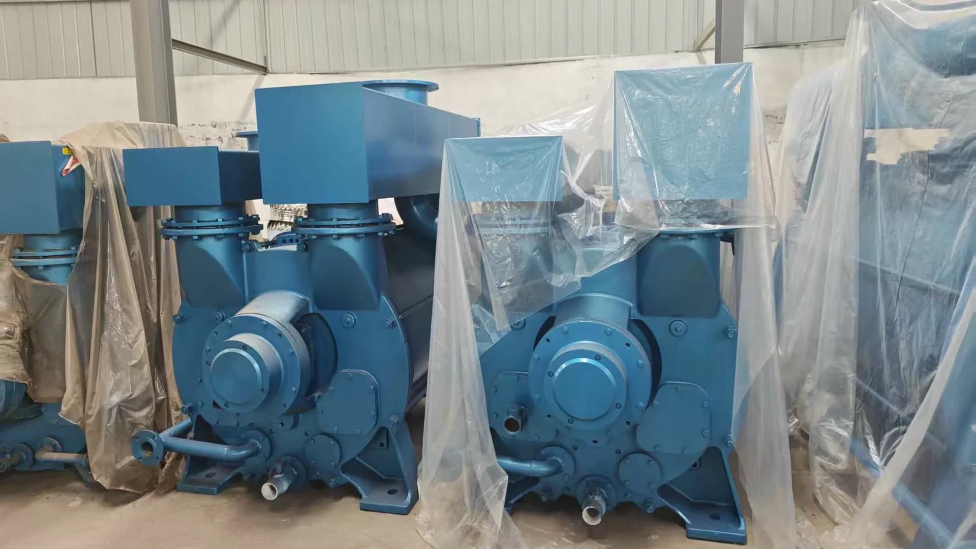 Blue water-ring vacuum pumps in a workshop, shown as general replacement-review equipment context and not a customer-specific shared-header configuration