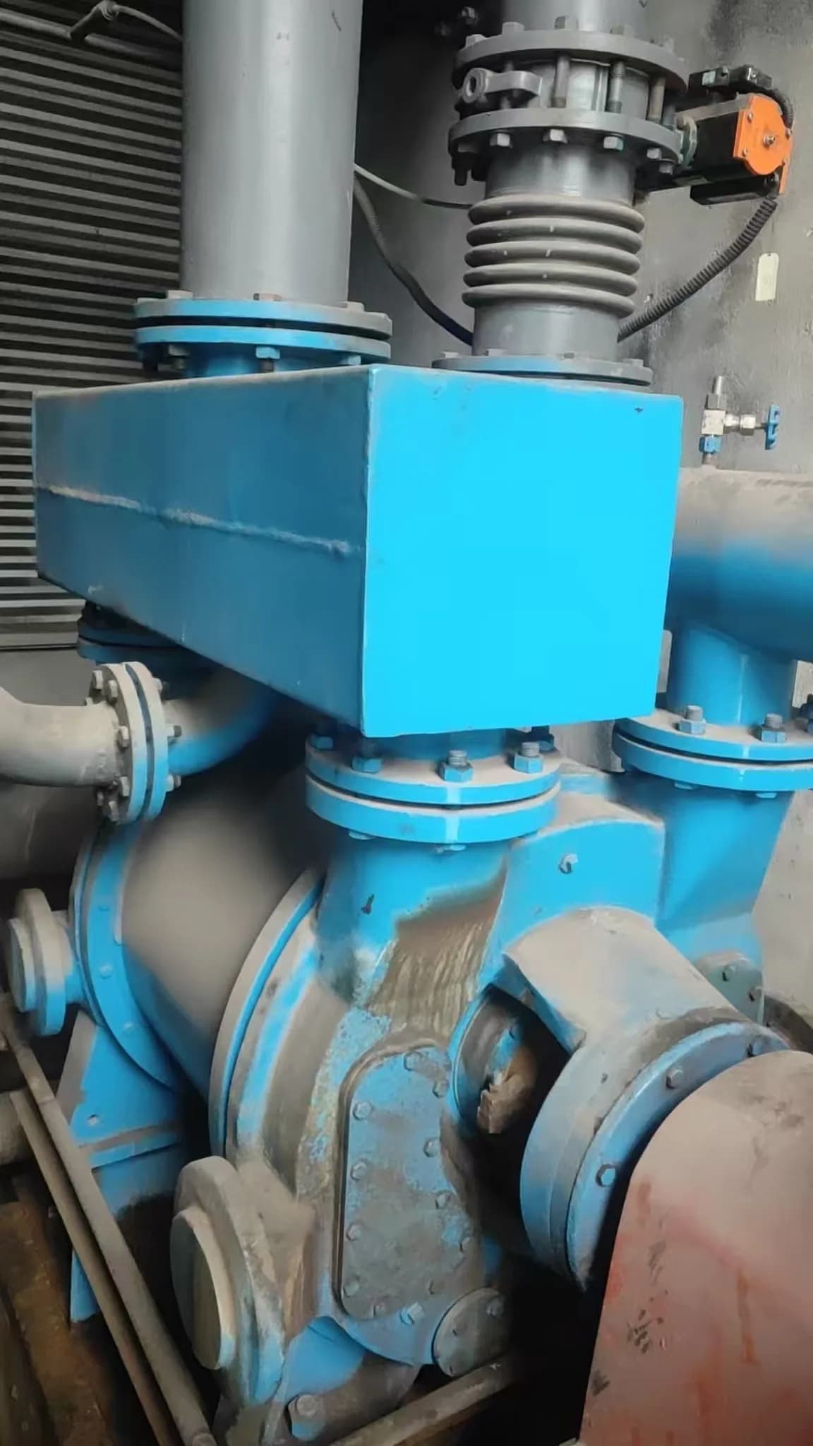 Blue liquid ring vacuum pump connected to process piping at a customer site