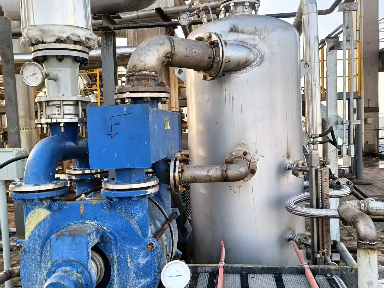 Existing water-ring vacuum pump installation at a customer site, showing the pump, separator vessel, piping, gauges, and water-loop connections; image illustrates an existing-system review, not a standard configuration.